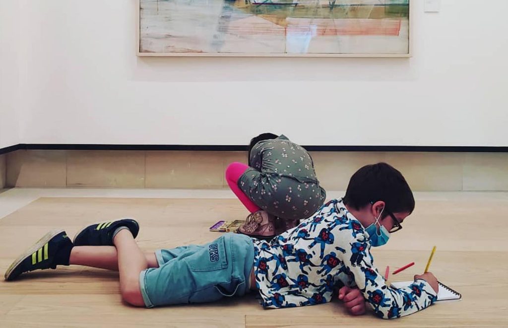 Foto di un bambino che scrive steso per terra sul pavimento della fondazione